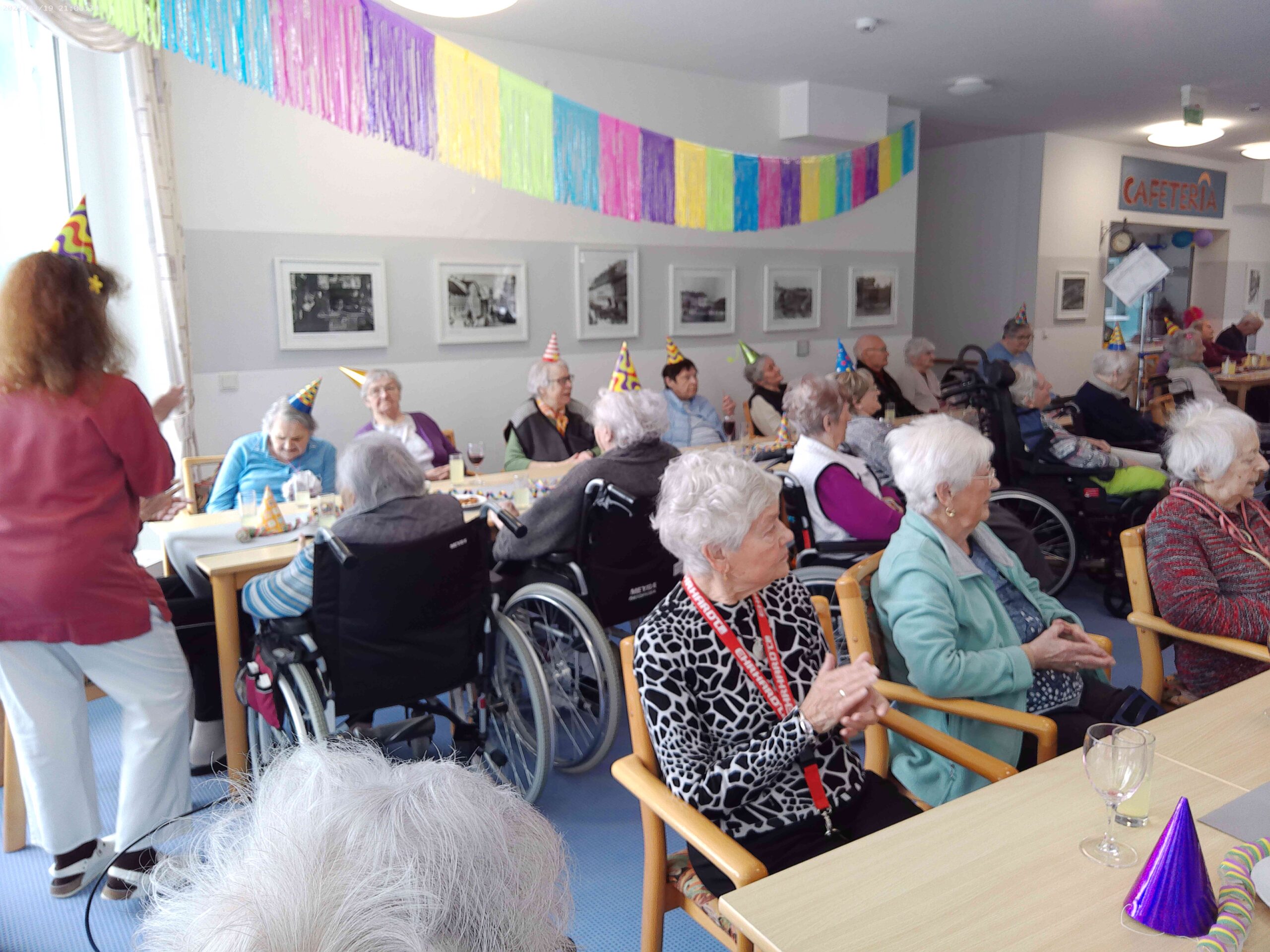 die Bewohner*innen sitzen im bunt geschmückten Partyraum